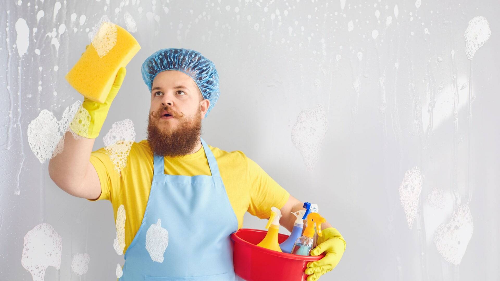 Funny man with a beard in an apron washing