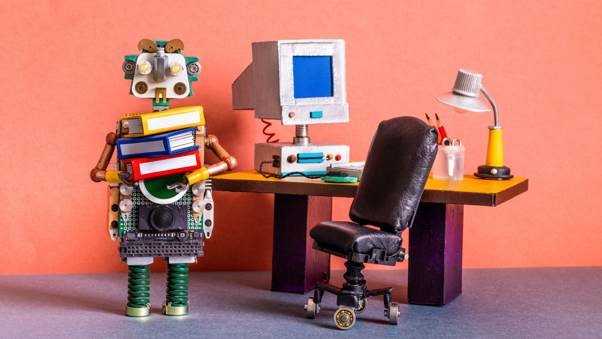 robot holding books standing beside desk
