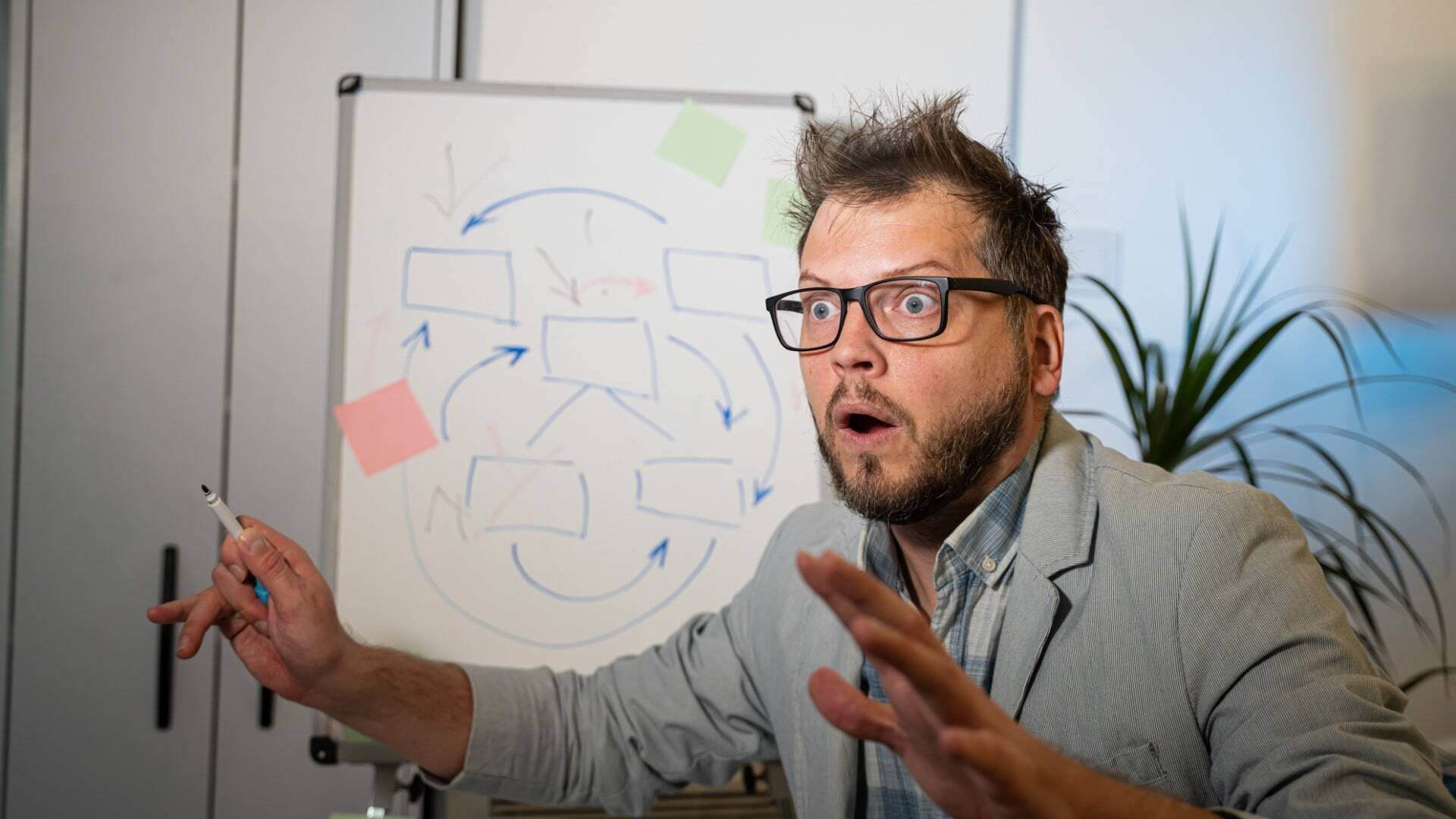 lecturer with glasses shows graphs on the board