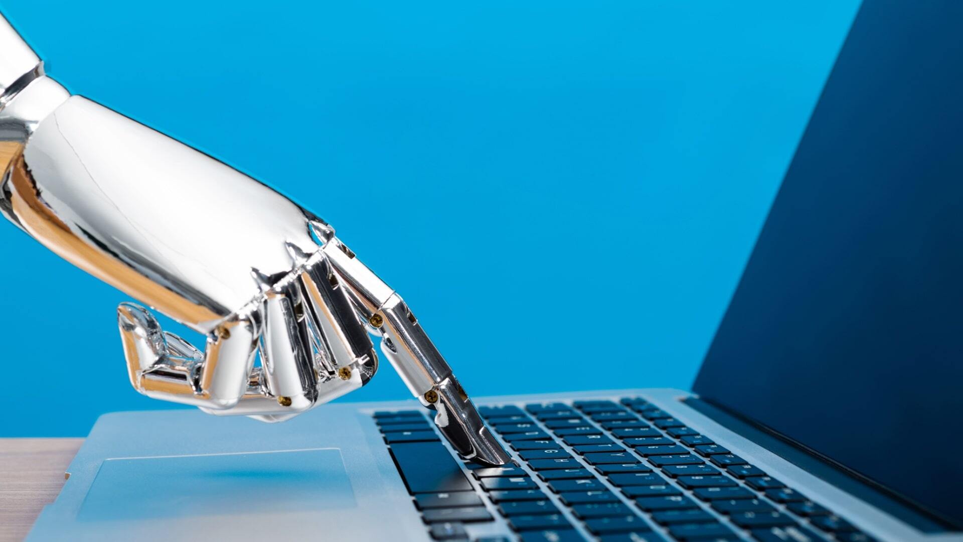 Robot hand typing on a laptop keyboard, representing AI-generated responses and automation.
